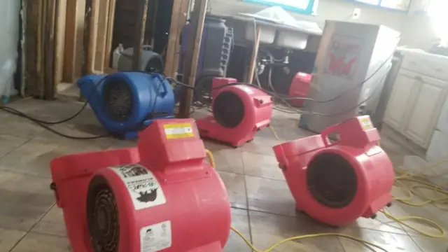 Red air movers set up on a tile floor to dry a wet room